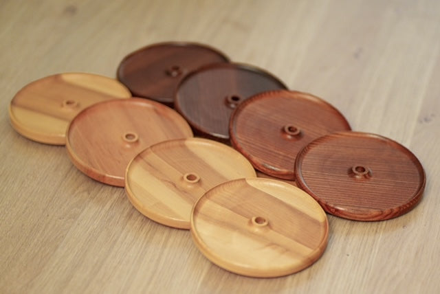 Quatre couvercles d’apéro en érable et quatre en frêne torréfié, ronds avec trou pour paille, présentés sur une table en bois.